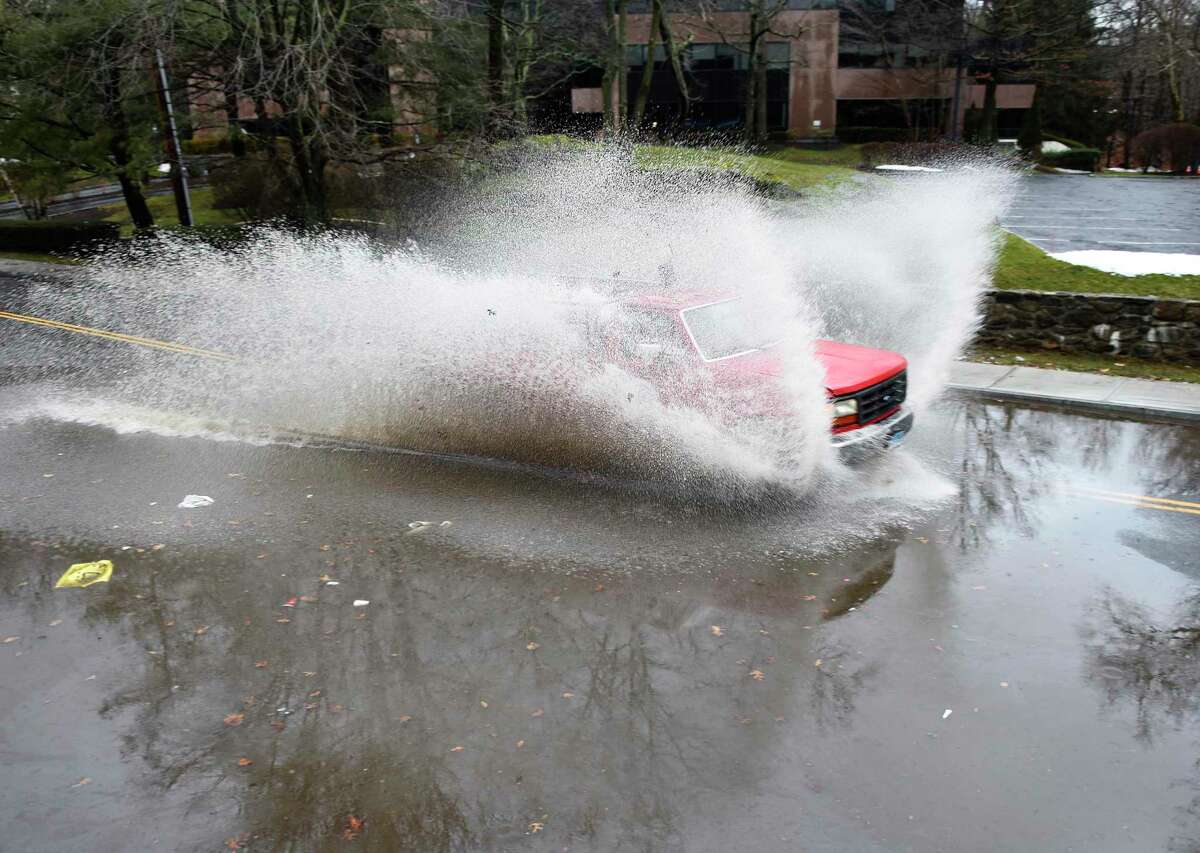 A truck powers through a deep puddle on a road temporarily closed due to flooding in Greenwich, Conn. Monday, Jan. 17, 2022. A winter storm hit the area early Monday morning, leaving a small amount of snow, followed by rain and eventually sunshine. The storm caused minor flooding and downed trees.