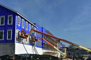 On boom lifts, crews continue work on a southern facade of Darien Crossing on Thursday, Jan. 13, 2022, in Darien, Conn.