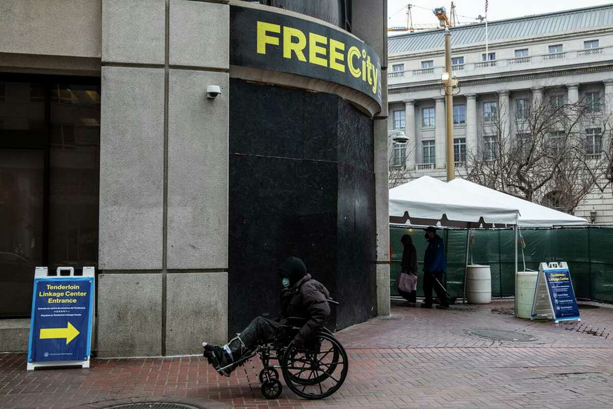 A person in a wheelchair rolls past Tenderloin Linkage Center at United Nations Plaza in San Francisco, Calif.