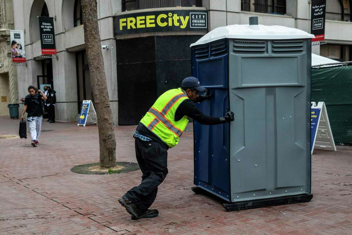 A worker pushes a porta potty into Tenderloin Linkage Center at United Nations Plaza ahead of its opening in San Francisco, Calif. Tuesday, Jan. 18, 2022. The center, part of the City’s Tenderloin emergency declaration, provides people on the streets with treatment, housing and resources.
