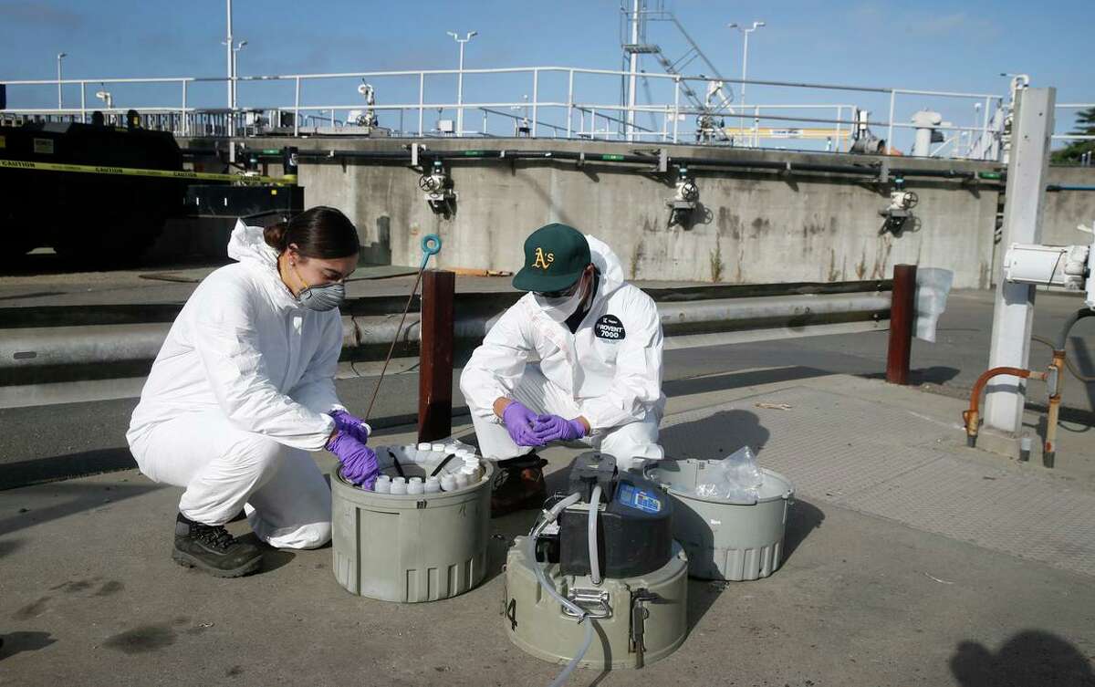 Wastewater control inspectors with East Bay Municipal Utility District gather effluent to be analyzed for coronavirus genetic material.