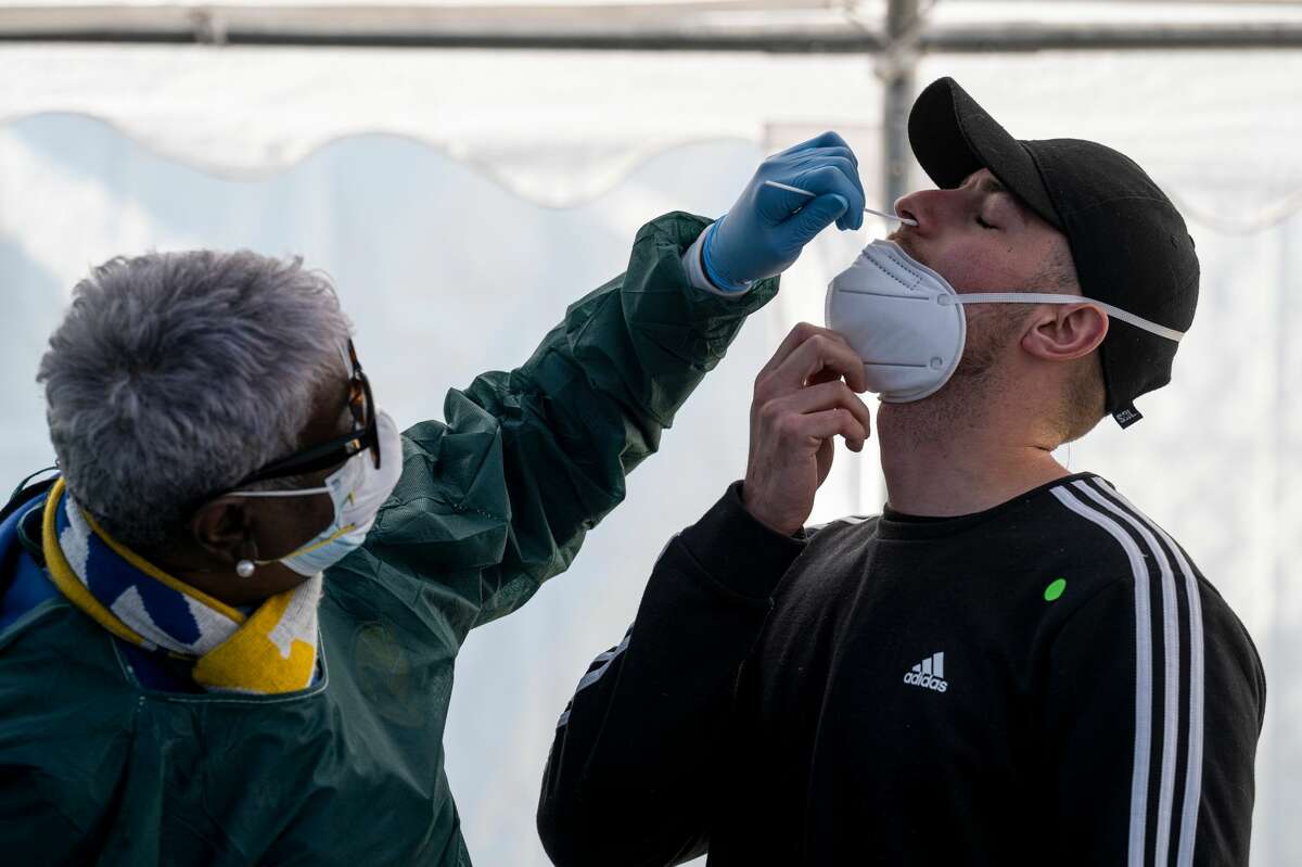 A health care worker administers a COVID-19 test at testing site in San Francisco on Jan. 10, 2022.