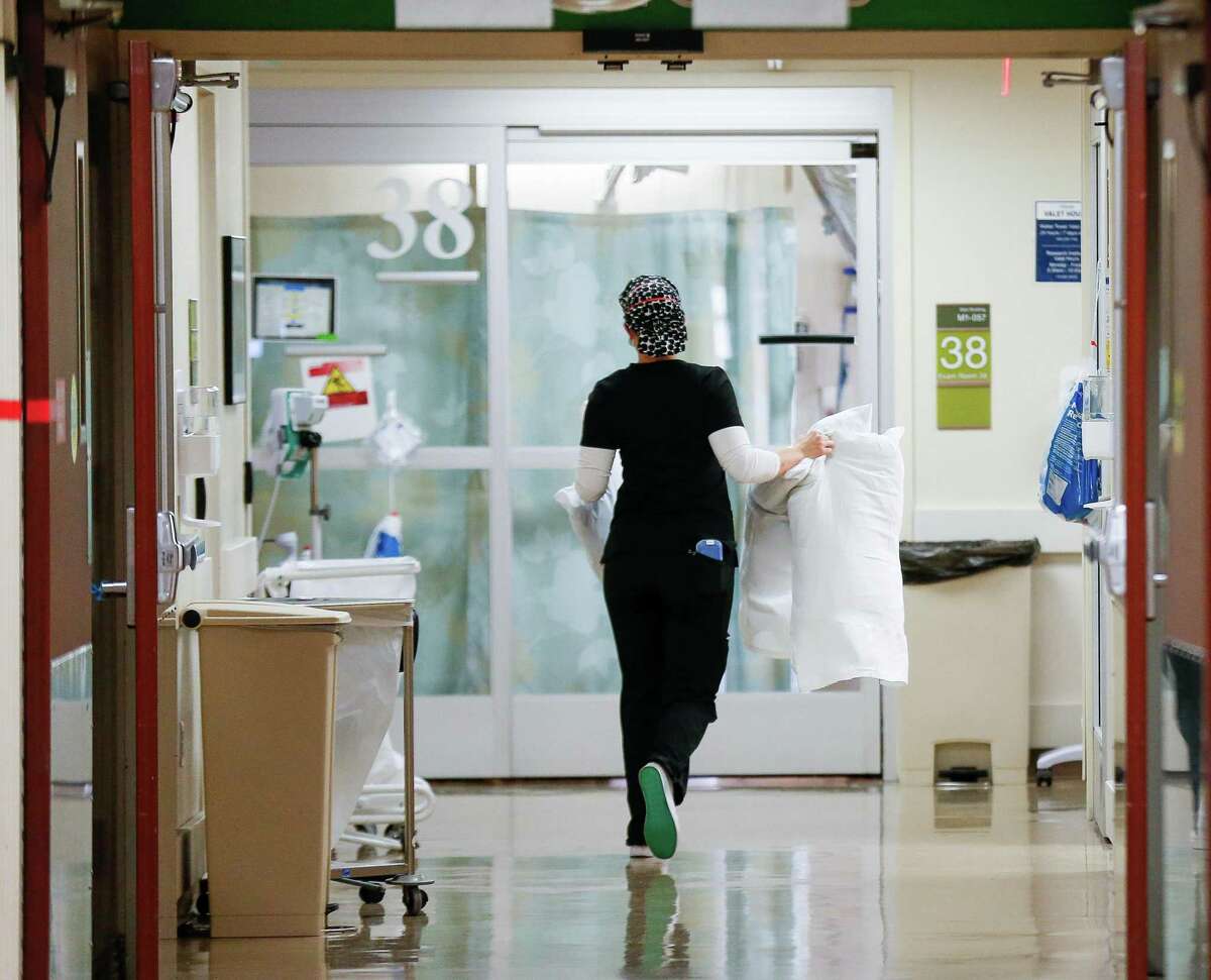 A medical professional carries three pillows inside the Emergency Department at Houston Methodist Hospital on Tuesday, Dec. 21, 2021, in Houston.
