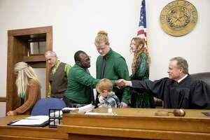 Malcom Morgan-Petty thanks Judge Benton Eskew at an adoption ceremony at the Bastrop County Courthouse in Bastrop on Tuesday November 9, 2021.  Malcom adopted Brian Haynes-Morgan-Petty III, 16.  Brian’s siblings Jordan Petty, 6, and Skye Petty, 12, were adopted by Malcom’s adoptive parents Kent and Dixie Petty, left, Several children who were in the care of the Texas Department of Family and Protective Services were adopted by families during the Bastrop County Adoption Day, which is part of National Adoption Month.   National Adoption Month celebrates adoptions and highlights the need for adoptive families.