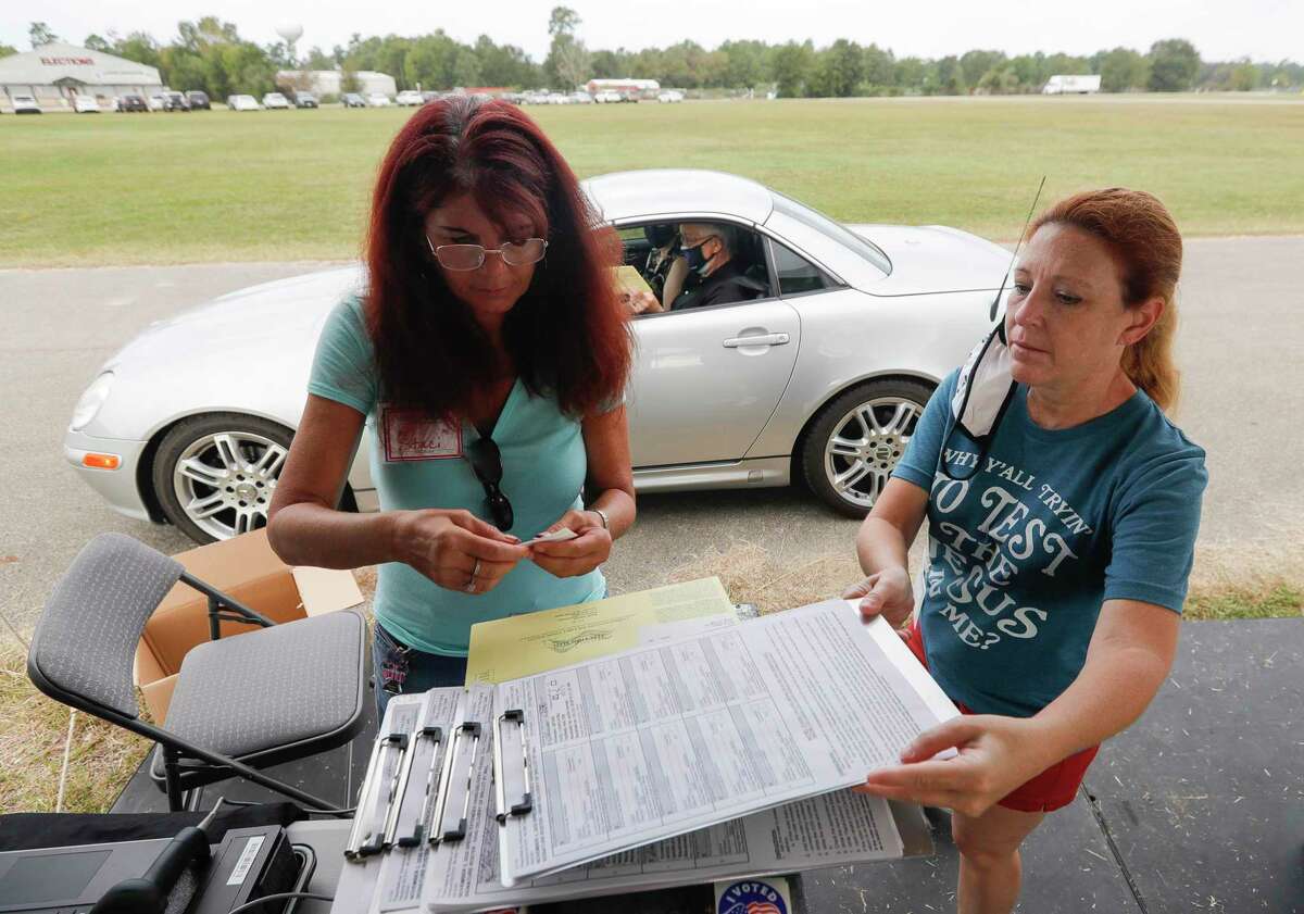 Election Clerks Stacti Leikam, left, and Tracy Kelly check paperwork and signatures as she helps residents security submit mail-in ballots, Thursday, Oct. 15, 2020, in Conroe. Texas counties may collect mail-in ballots at one location, a federal appeals court ruled on Oct. 12, upholding an order from Gov. Greg Abbott to limit absentee ballot locations.
