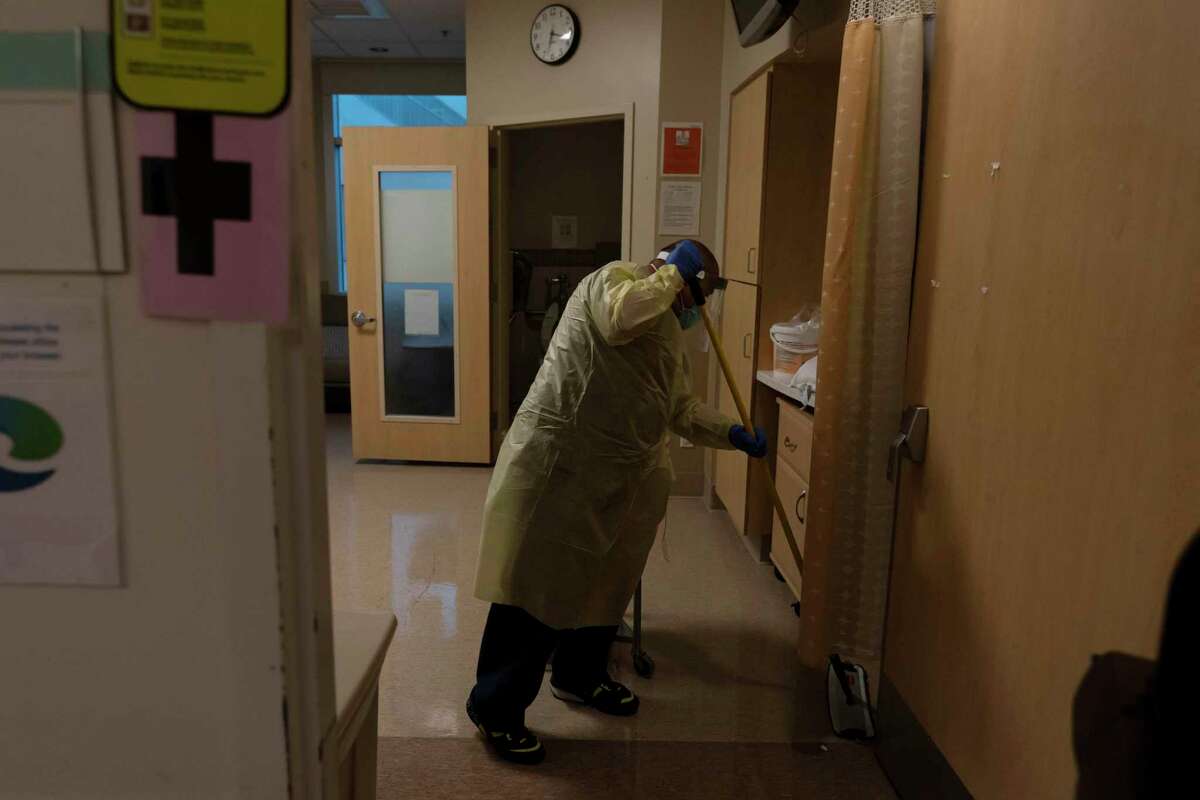 Environmental technician Gerardo Velazquez cleans a room after a COVID-19 patient transferred out of it at Providence Holy Cross Medical Center in Los Angeles.