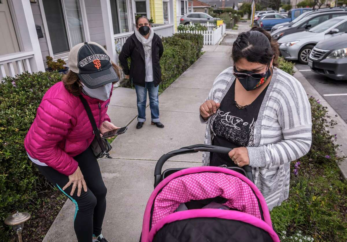 Lilli Rey (left) and Pati Ramirez bid farewell to Maria Vega, who stopped with her 9-month-old daughter at the offices of Ayudando Latinos A Soñar in Half Moon Bay.