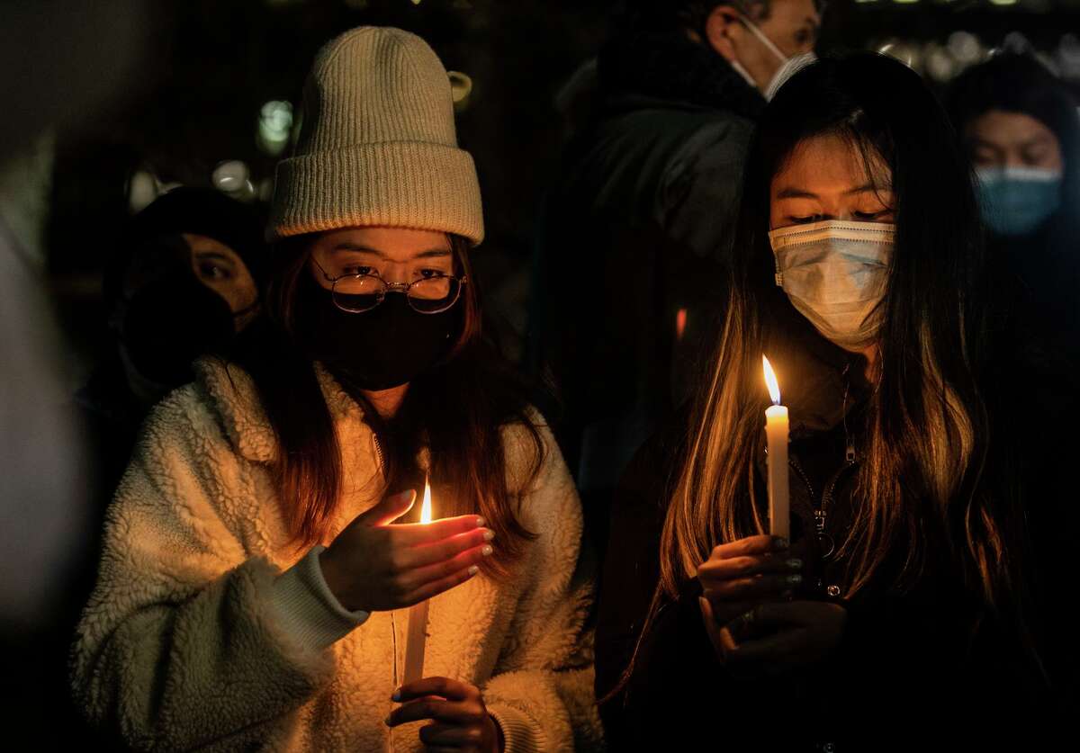 Attendees Brittany (left) and Emily hold candles during a candlelight vigil for Michelle Go in Chinatown.