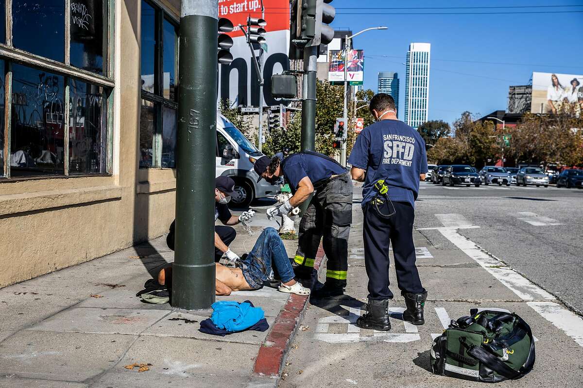 Paramedics with the San Francisco Fire Department tend to a patient covered in feces on a suspected opioid-related medical call in Downtown San Francisco, California Thursday, Oct. 28, 2021.