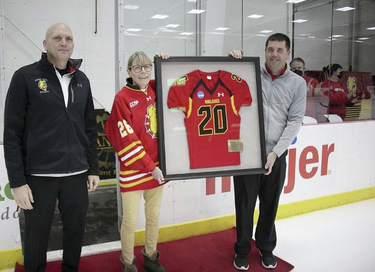 Dr. Melissa DeNiel was recently recognized for her 20 years of service as a team doctor for Ferris State University athletics during a FSU hockey game. Dr. DeNiel is an orthopedic surgeon with Spectrum Health. She’s worked with FSU athletes from all 17 varsity programs for the Bulldogs. Presenting the commemorative jersey and plaque to Dr. DeNiel is FSU athletic director Steve Brockelbank, left, and assistant athletic director for sports medicine, Brett Knight, at right.