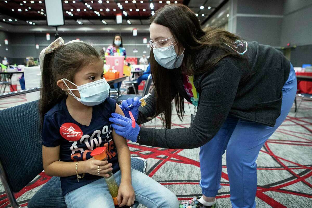 Melanie Alarcon, 5, receives a COVID-19 vaccination from medical assistant Sydney Jensen to during a city-wide vaccination clinic at the George R. Brown Convention Center Friday, Dec. 17, 2021 in Houston. Texas Children’s Hospital and the City of Houston hosted a free citywide COVID-19 vaccine clinic for attendees aged 5 and older. Eligible participants were able to receive first or second doses of the Pfizer or Moderna vaccine, or an additional dose of the Pfizer or Moderna vaccine, or a booster dose of the Pfizer or Moderna vaccine, as needed.