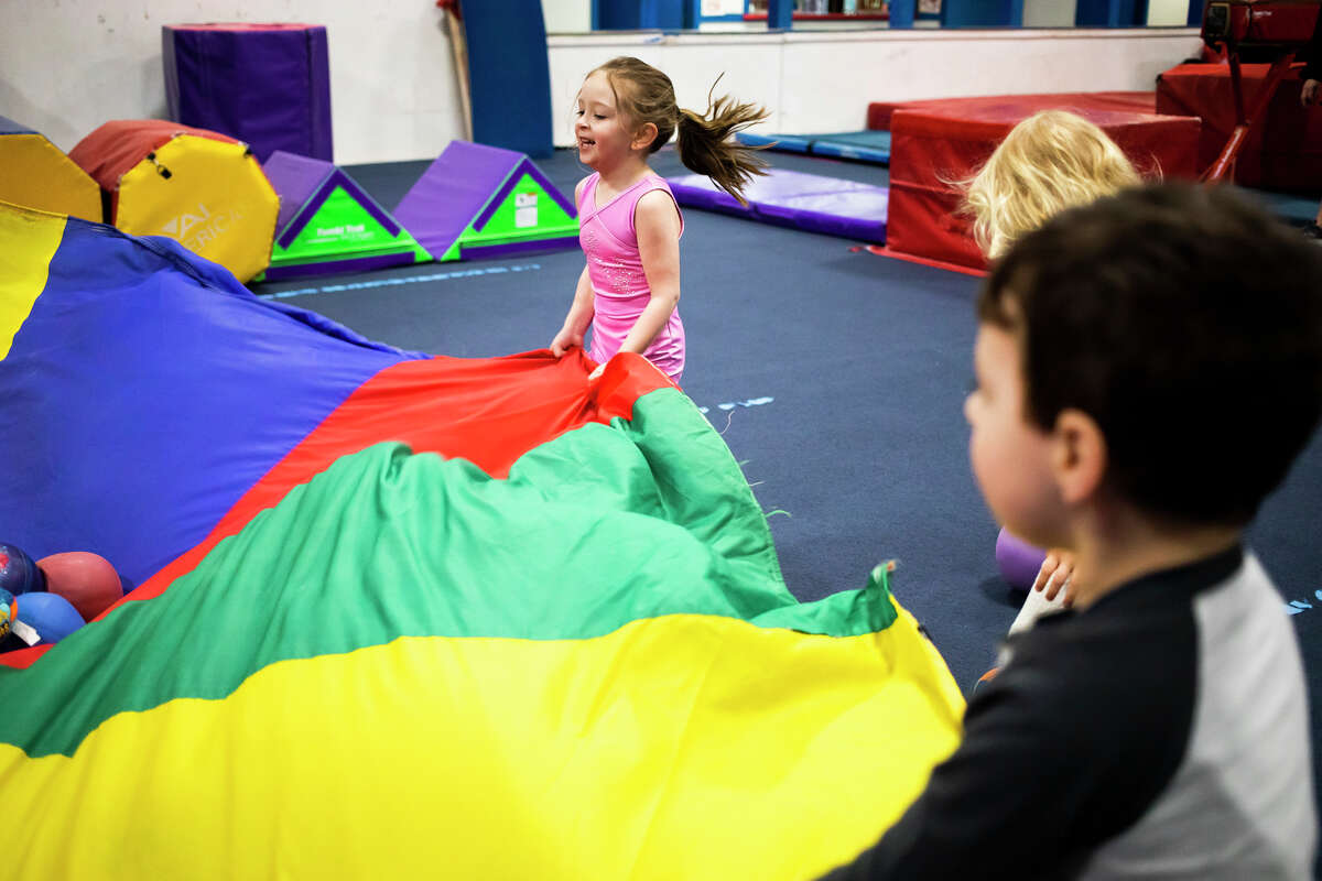 Avery Hospodar, 4, smiles while playing with a large parachute Wednesday, January 19, 2022 during a weekly preschool play session at Midland Gymnastics Training Center.