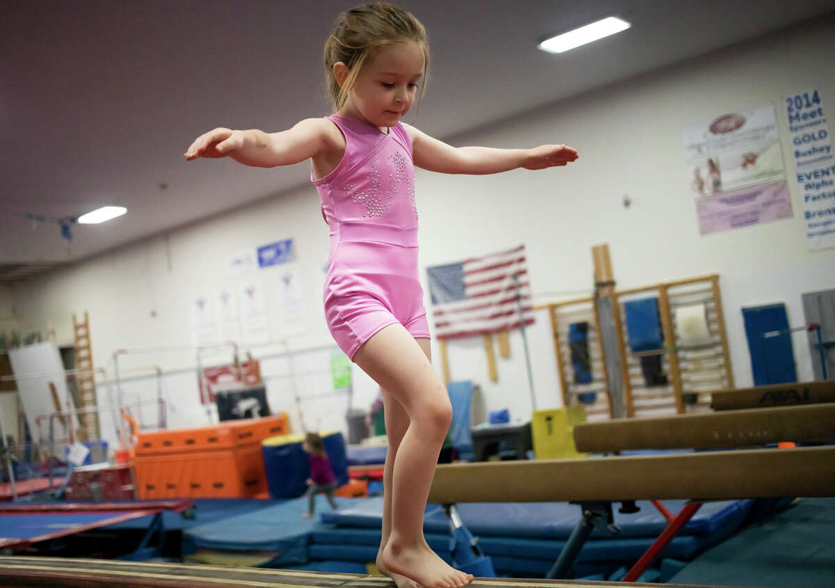 Avery Hospodar, 4, crosses the balance beam while playing Wednesday, January 19, 2022 during a weekly preschool play session at Midland Gymnastics Training Center.