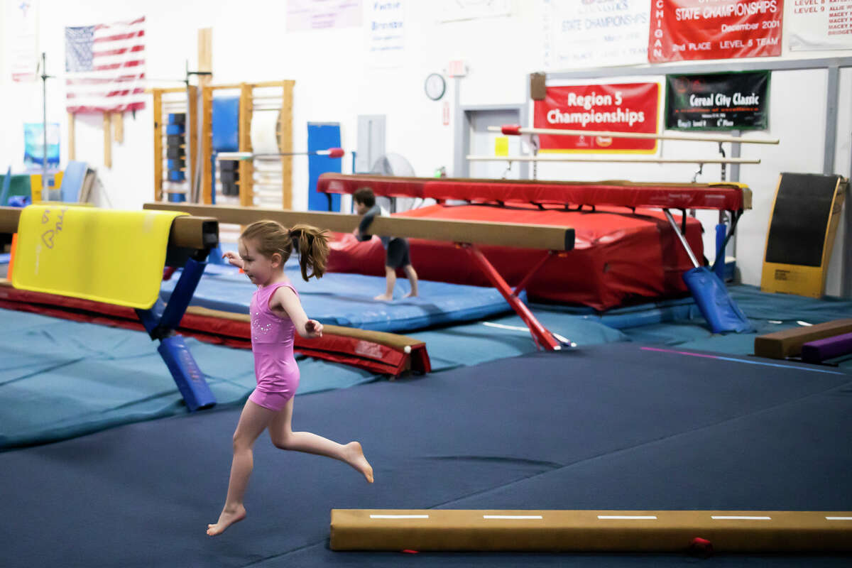 Avery Hospodar, 4, jumps off a balance beam while playing Wednesday, Jan. 19, 2022 during a weekly preschool play session at Midland Gymnastics Training Center.
