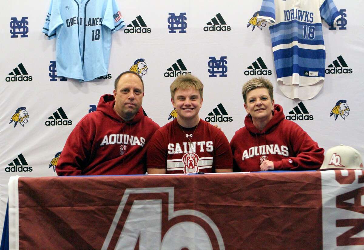 Morley Stanwood senior Aaron Moore (center), sits with his parents, Rick (left) and Nancy, as he signs his letter of intent Wednesday morning to play baseball at Aquinas College.