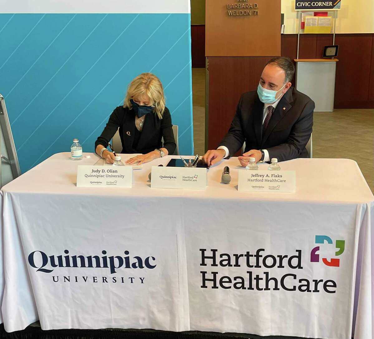 Quinnipiac University President Judy D. Olian, left, and Hartford Healthcare CEO Jeffrey Flaks, right, sign an agreement solidifying a partnership to expand educational programs Jan. 19, 2022 in North Haven.