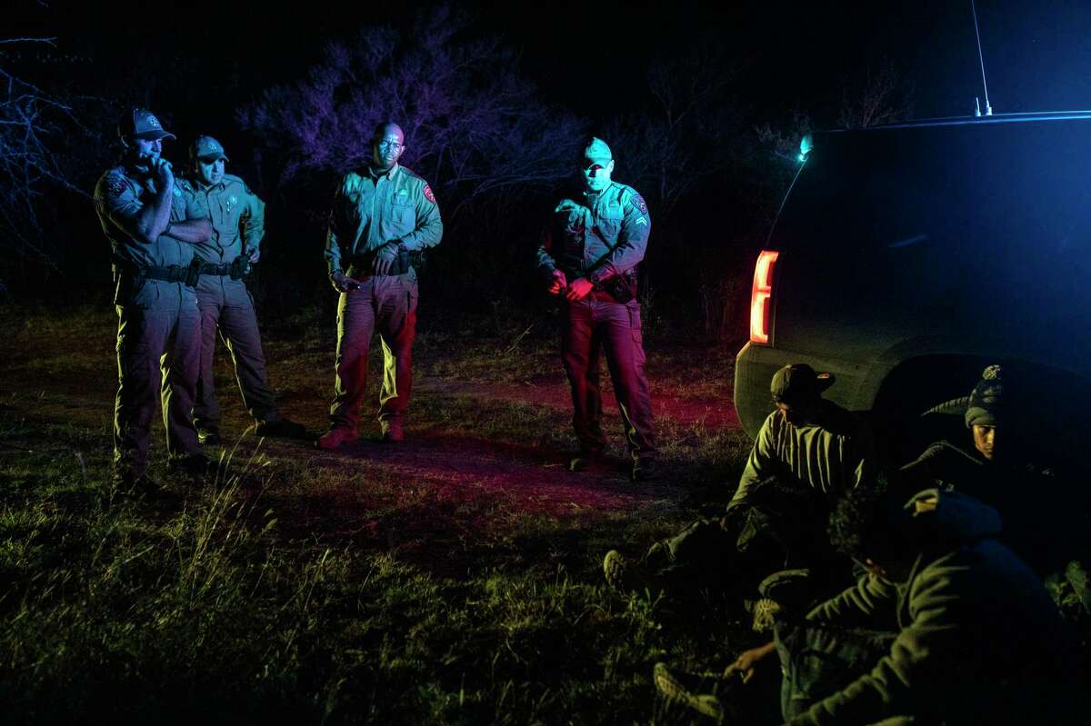 -- STANDALONE PHOTO FOR USE AS DESIRED WITH YEAREND REVIEWS -- A group of migrants wait after being apprehended by officers with the Texas Department of Public Safety in Kinney County, Texas, on Nov. 17, 2021. Ranchers signed up with the department to allow the state police to patrol their properties and arrest people for trespassing. (Kirsten Luce/The New York Times)