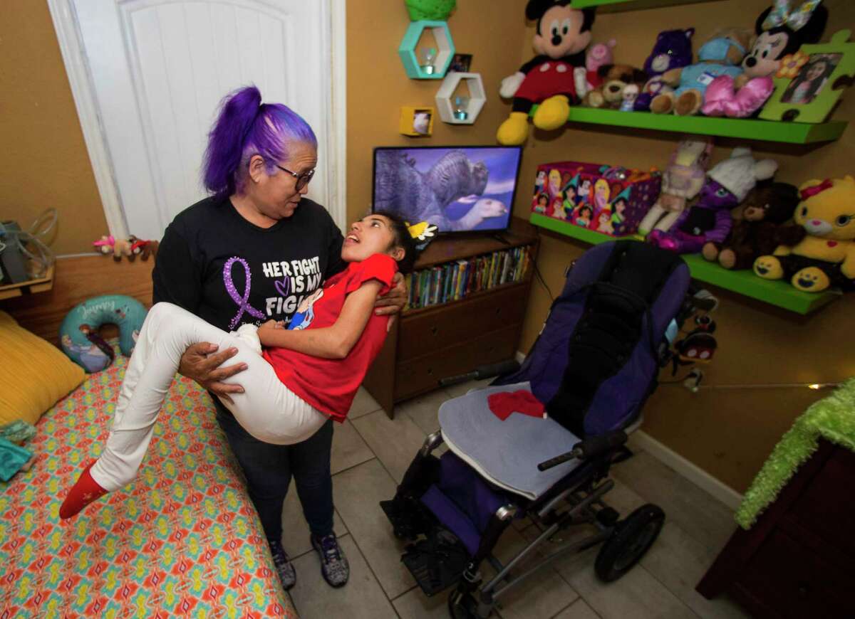 Olivia Esparza lifts her daughter, Diana Santana, 21, helping her to her wheelchair Saturday, April 3, 2021 in Houston. After a couple days without power in her home, Esparza made the decision to take her wheelchair-bound daughter to Florida to keep her safe from any difficulties caused by the deep freeze and the power outages that came with it.