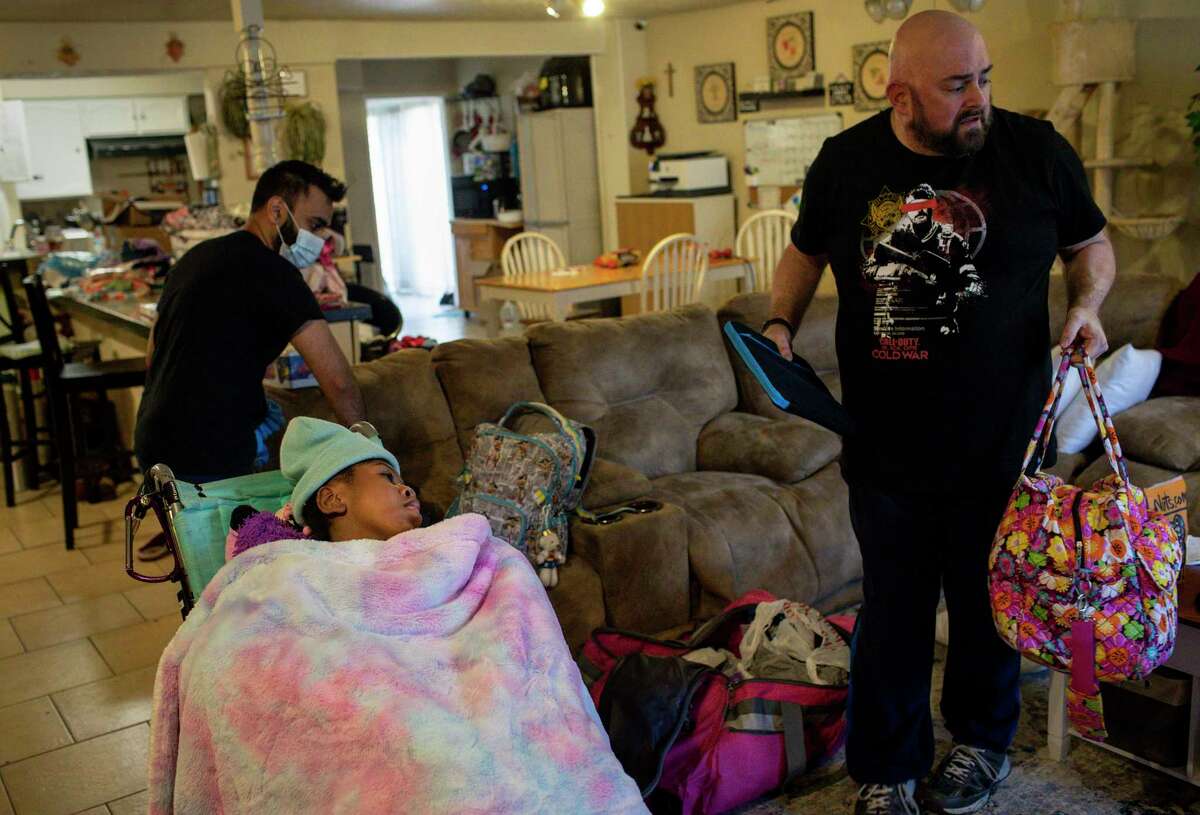 Stan Cheevers, right, unpacks after returning home with his daughter Hailey Cheevers, 11, as Samir Haq, a home-health nurse, gets Hailey settled in the home Friday, Feb. 19, 2021, in Houston. Pipes broke in the cold weather causing parts of the ceiling to collapse.