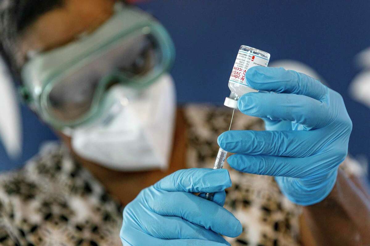Registered nurse Joyce Turner draws a dose of the Moderna COVID-19 vaccine as she prepares to administer a booster shot to Arturo Coronel, not pictured, during a free drive-up vaccine clinic held at Compass Rose Ingenuity Campus Charter School in San Antonio, Texas, Wednesday afternoon, Jan. 5, 2022. The Health Collaborative, Lela Pharmacy, and the YWCA teamed up to offer Pfizer, Modern and Johnson & Johnson vaccines to eligible people from 1-4 p.m. Wednesday. Another free vaccine clinic will be held at the Compass Rose campus on Friday, Jan. 28.