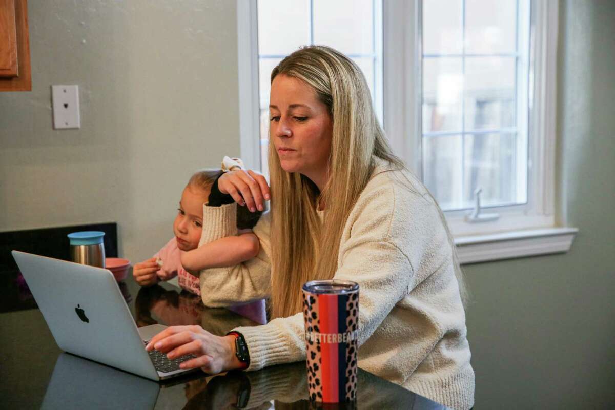 Michelle Caruso works on her computer while in quarantine with her four-year-old daughter at their home in Livermore, Calif. This month, Michelle, her daughter, 19-month-old son and husband were sick with COVID-19. While her daughter continues to test positive, Michelle is forced to stay home joining many parents who have had their work and routines upended due to the omicron surge.