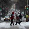A person and their dog cross Houston Street Thursday, Feb. 18, 2021 as snow grips the city for the second time in a week, the result of an arctic air mass that sent temperatures plummeting and resulted in rolling blackouts across the city and the state. At one point about 1/3 of all CPS Energy customers were without electricity.