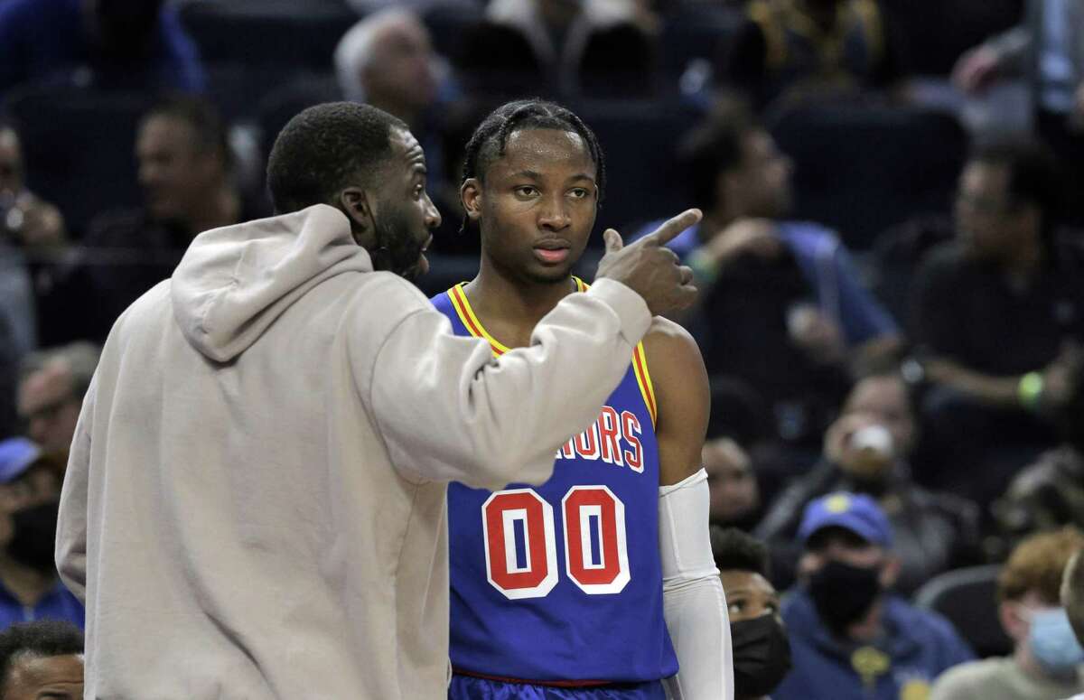 Draymond Green (23) chats with Jonathan Kuminga (00) after he returned to the bench when he was called for this third foul in the first half as the Golden State Warriors played the Detroit Pistons at Chase Center in San Francisco, Calif., on Tuesday, January 18, 2022.