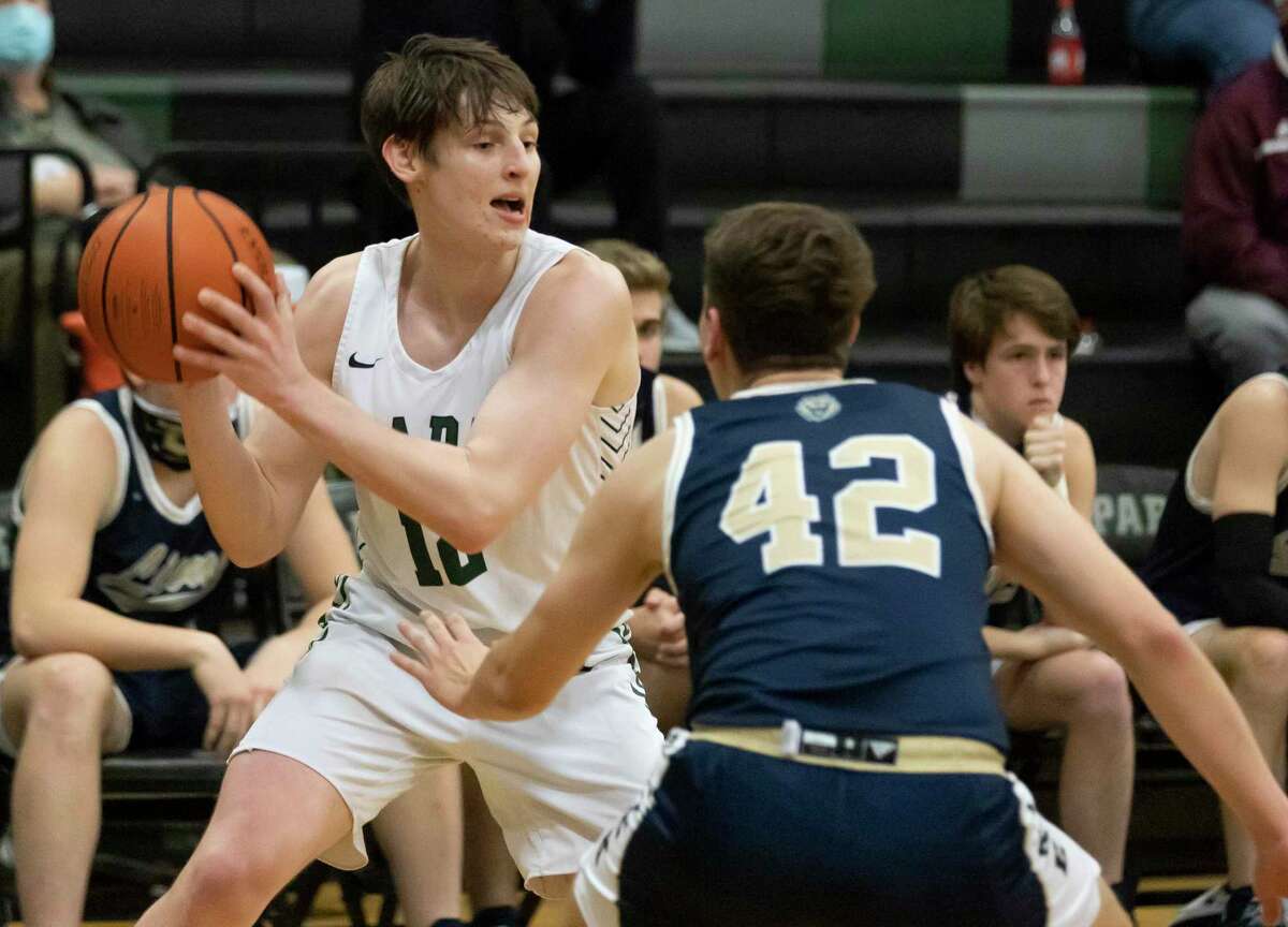 Kingwood Park Kyle Connelly (12) passes the ball despite pressure from Lake Creek small forward Hudson Boyd (42) during the second quarter of a District 20-5A boys basketball game at Kingwood Park High School, Wednesday, Jan. 27, 2021 in Kingwood.