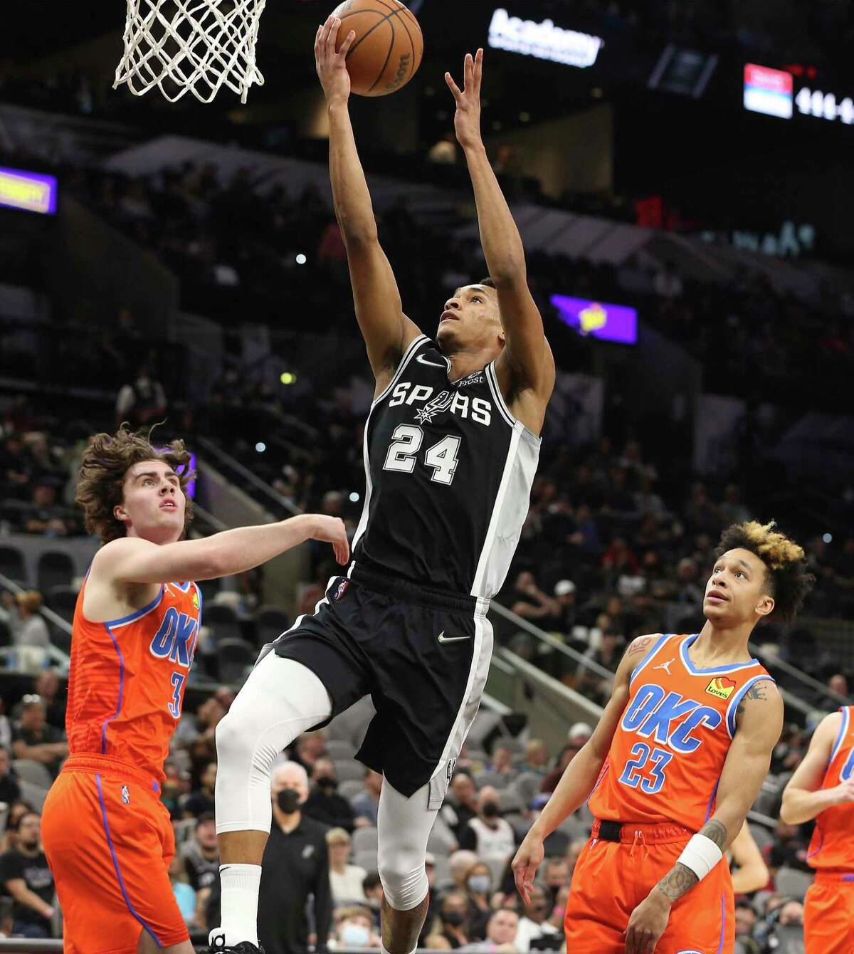 Spurs' Devin Vassell (24) drives and scores against Oklahoma City Thunders' Josh Giddey (03) and Tre Mann (23) during their game at the AT&T Center on Wednesday, Jan. 19, 2022.