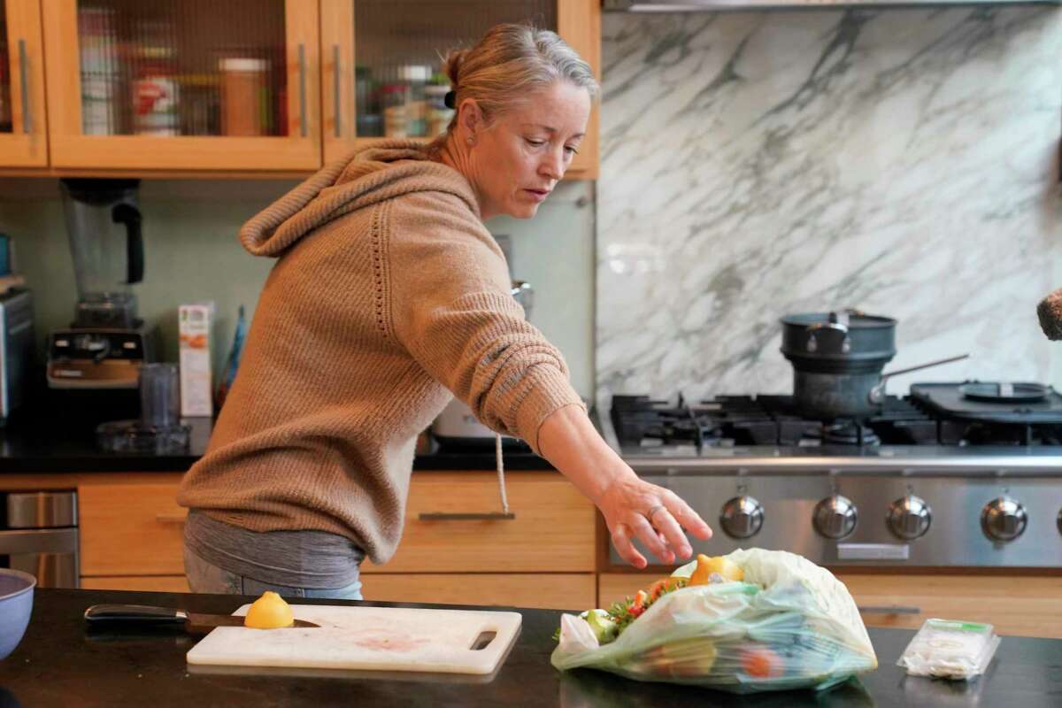 Joy Klineberg tosses a lemon peel into a bag to be used for composting while preparing a family meal at her home in Davis, Calif., Tuesday, Nov. 30, 2021. In January 2022, new rules take effect in California requiring household food recycling designed to reduce greenhouse gas emissions from landfills. Davis residents like Klineberg must already put their food waste into the yard waste bin to be collected for composting. (AP Photo/Rich Pedroncelli)