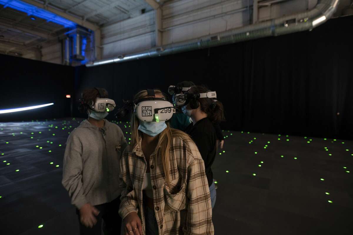 A woman walks through the space walk portion of the virtual reality room in The Infinite Tuesday, Dec. 21, 2021, at Sawyer Yards in Houston.