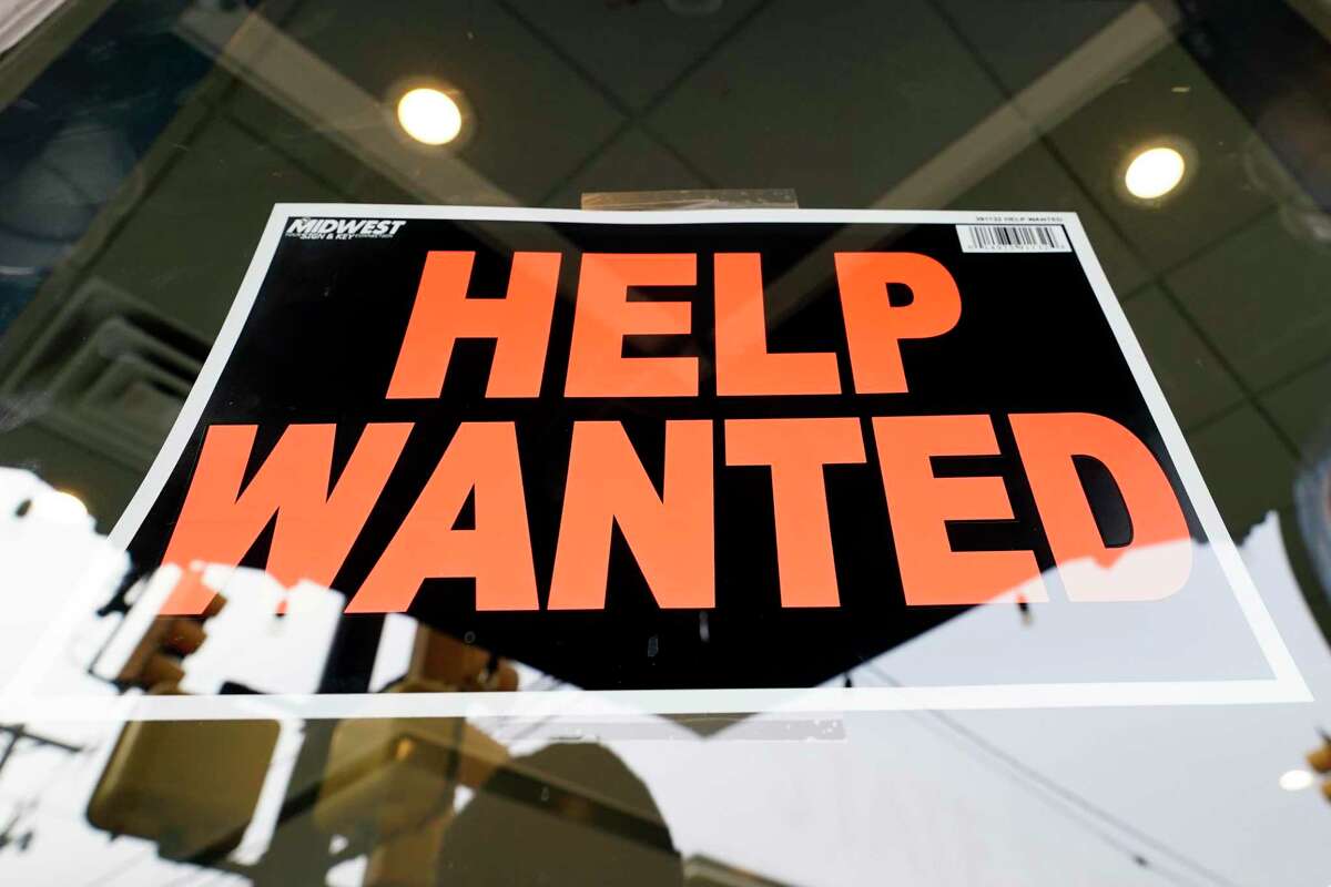 A help wanted sign is posted on a restaurant.