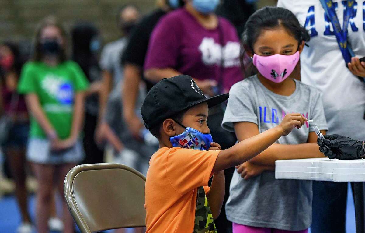 Kevin Gomez puts his nasal swab into a container for a COVID-19 test as his sister, Darally, watches at the Alamo Convocation Center last August in preparation for the first day of school.