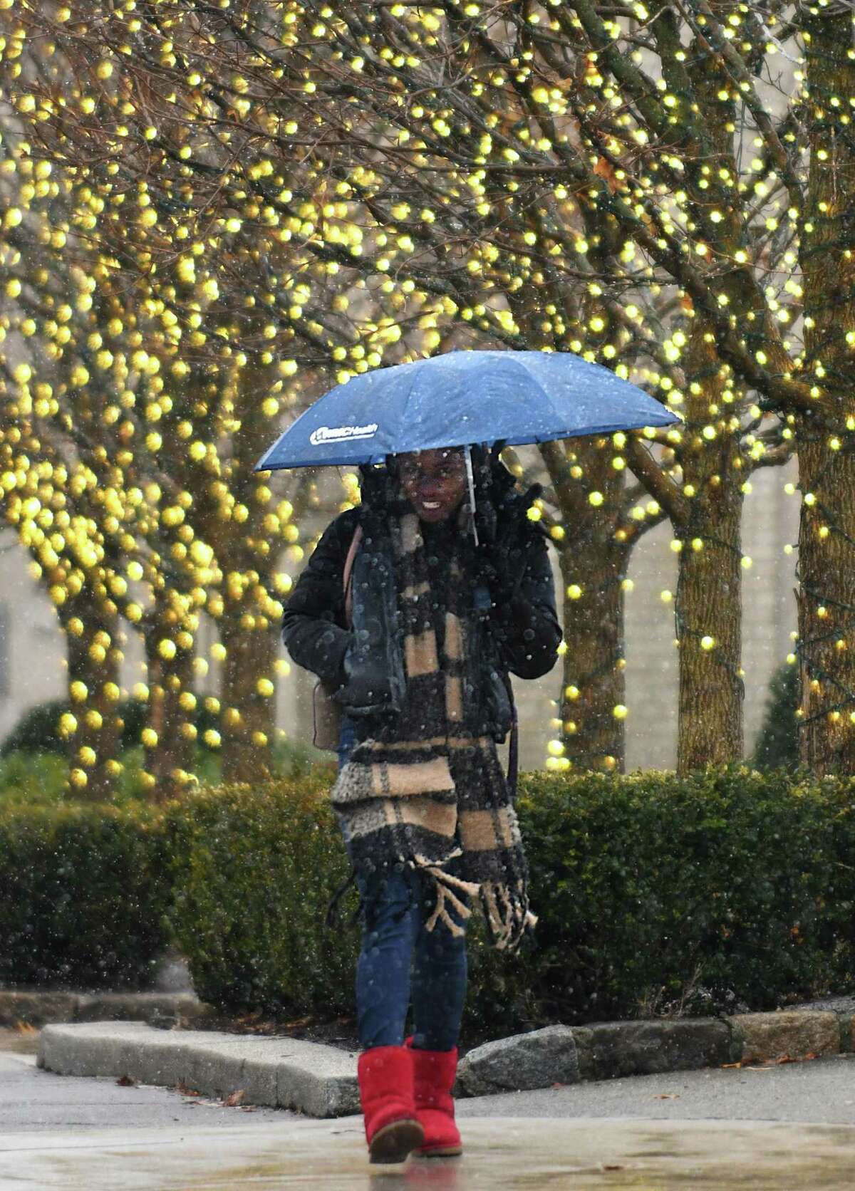 Stamford's Thamara Desronvil uses an umbrella to take cover from the snow in Greenwich, Conn. Thursday, Jan. 20, 2022. The area was hit with rain overnight that turned to light snow as temperatures dropped Thursday morning.