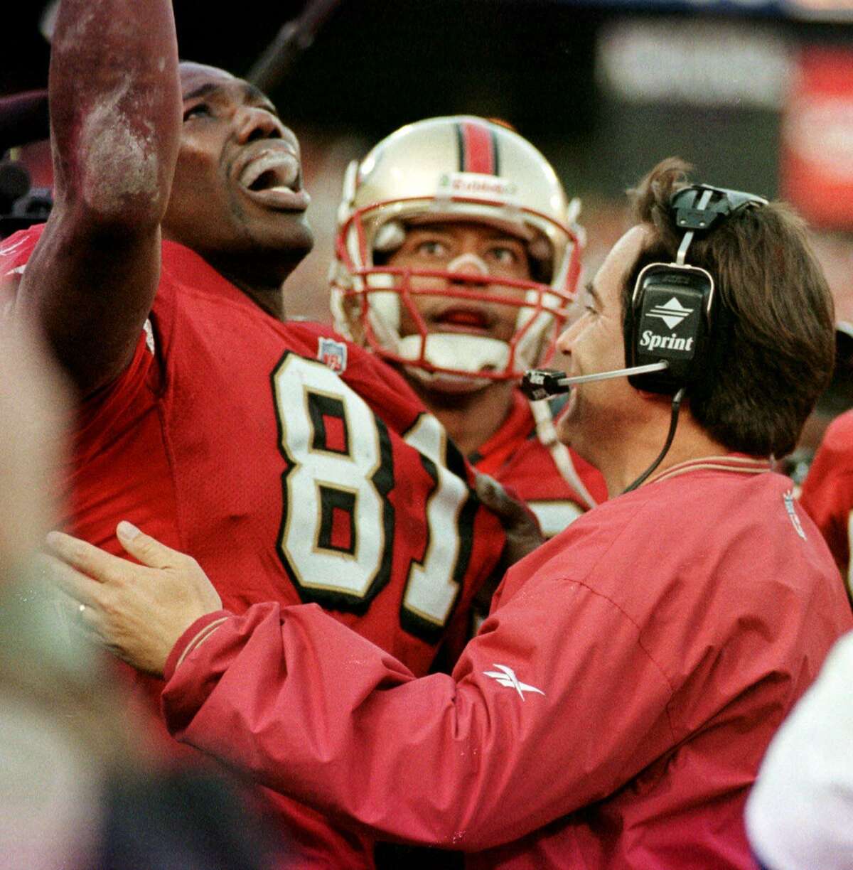 San Francisco 49ers' wide receiver Terrell Owens (81) is congratulated by head coach Steve Mariucci after catching the winning touchdown late in the fourth quarter of the NFC wild card playoff game at 3COM Park in San Francisco, Sunday, Jan. 3, 1999. The 49ers defeated the Green Bay Packers 30-27. Player in background is unidentified. (AP Photo/Ben Margot)