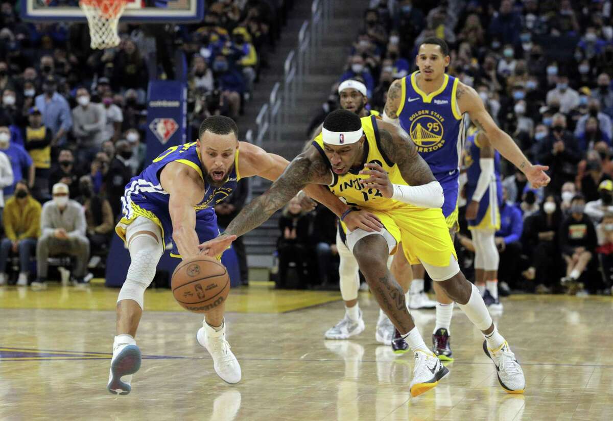 Stephen Curry (30) battles for a loose ball against Torrey Craig (13) in the final seconds of overtime as the Golden State Warriors played the Indiana Pacers at Chase Center in San Francisco, Calif., on Thursday, January 20, 2022. The Pacers defeated the Warriors 121-117