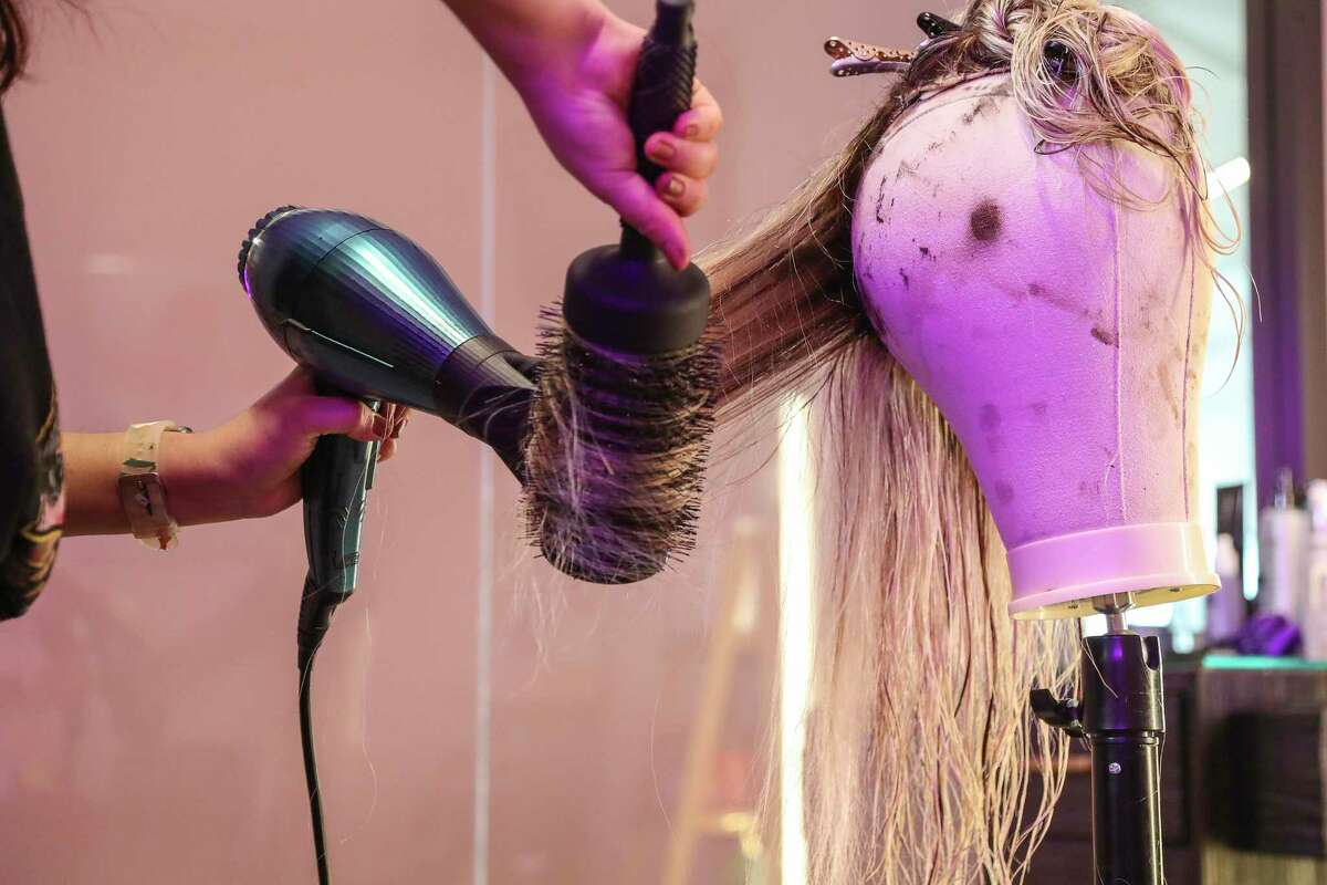 Stylist Hillary Fabela blow dries a client’s wig that she colored at Upgrade Boutique, a high-tech salon with customized hair options - on Almeda, Wednesday, Jan. 19, 2022 in Houston. Britney Winters, a Harvard MBA grad from Houston’s Cuney Homes in Third Ward, has been outfitting celebrities, such as Beyonce,Taraji P. Henson and Simone Biles, with hair extensions and wigs through her online platform.