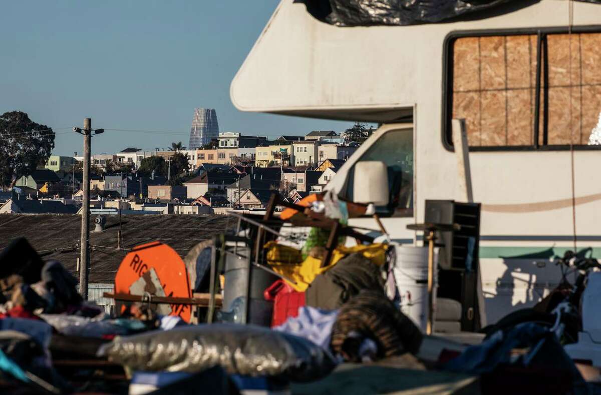 Left: Salesforce Tower is seen at a distance as Items are strewn on the ground at the City-run RV-site on Carroll Avenue in San Francisco, California Thursday, Jan. 20, 2022. Below: Sonya Rekula-Talone, who lives at the City-run RV site on Carroll Avenue, is seen during a meeting with other residents in San Francisco, California Wednesday, Jan. 19, 2022.