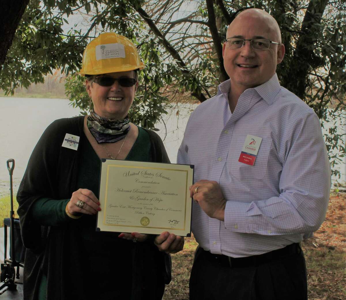 Rozalie Jerome, executive director of the Holocaust Garden of Hope project, and Mark Linabury, president of the Greater East Montgomery County Chamber of Commerce, display a proclamation from U.S. Senator Ted Cruz in honor of the ribbon-cutting for the garden project.