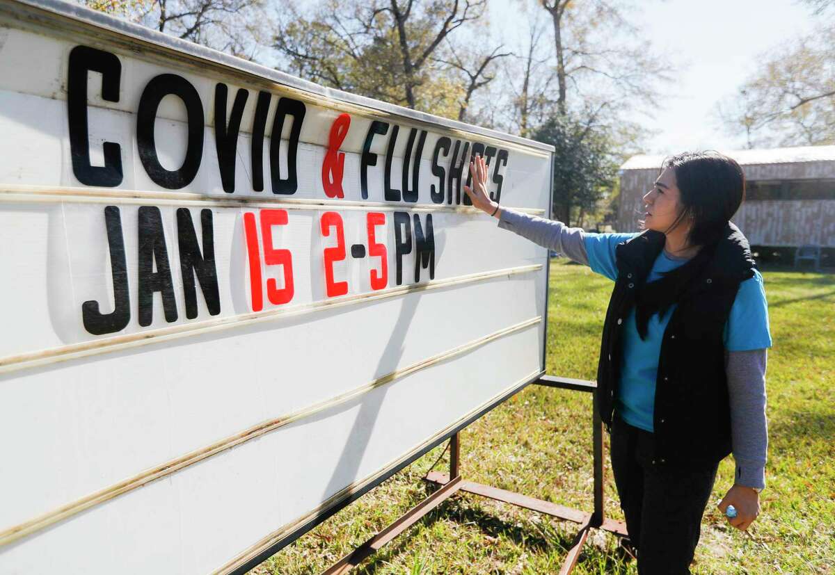 Rose Cervantes adjusts a sign in front of the Deerwood Community Center as she and other volunteers with the Texas Familias Council open a COVID-19 and flu vaccination clinic, Saturday, Jan. 15, 2022, in Conroe.