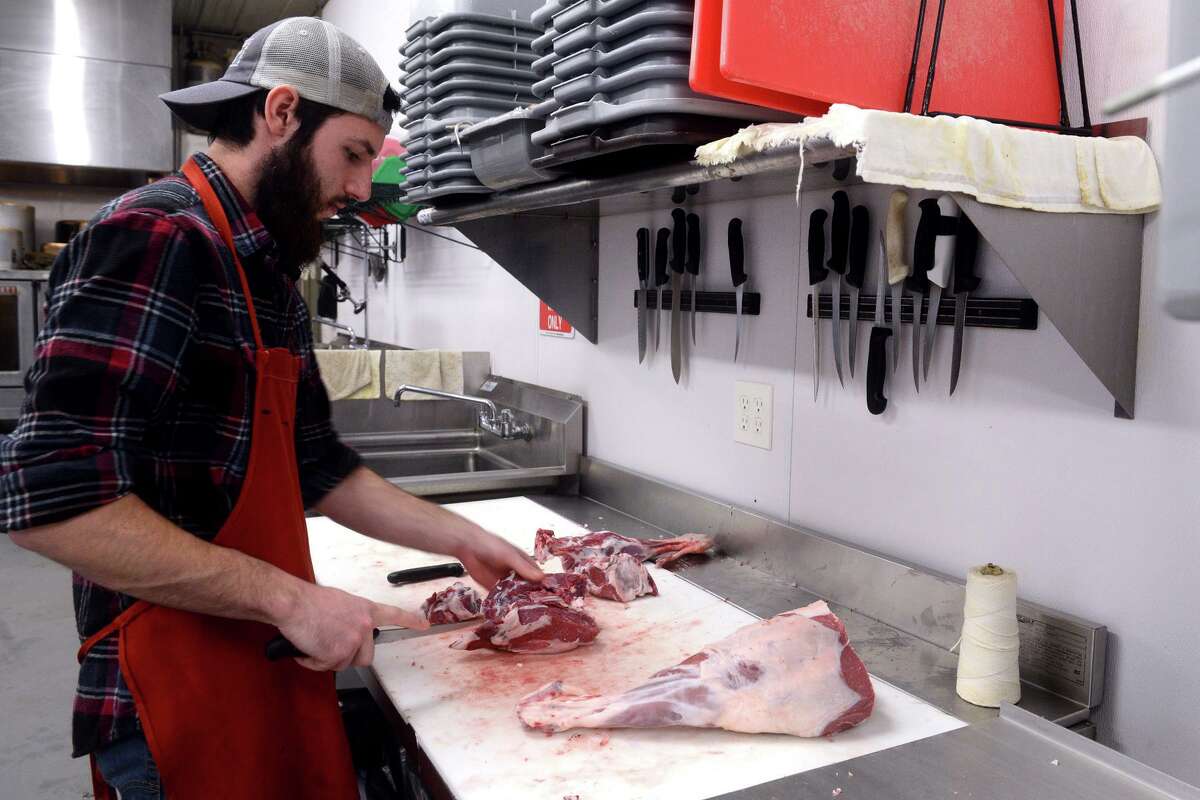 Tom Monahan cuts roast portions from a leg of lamb at Stone Gardens Farms, in Shelton, Conn. Jan. 20, 2022.