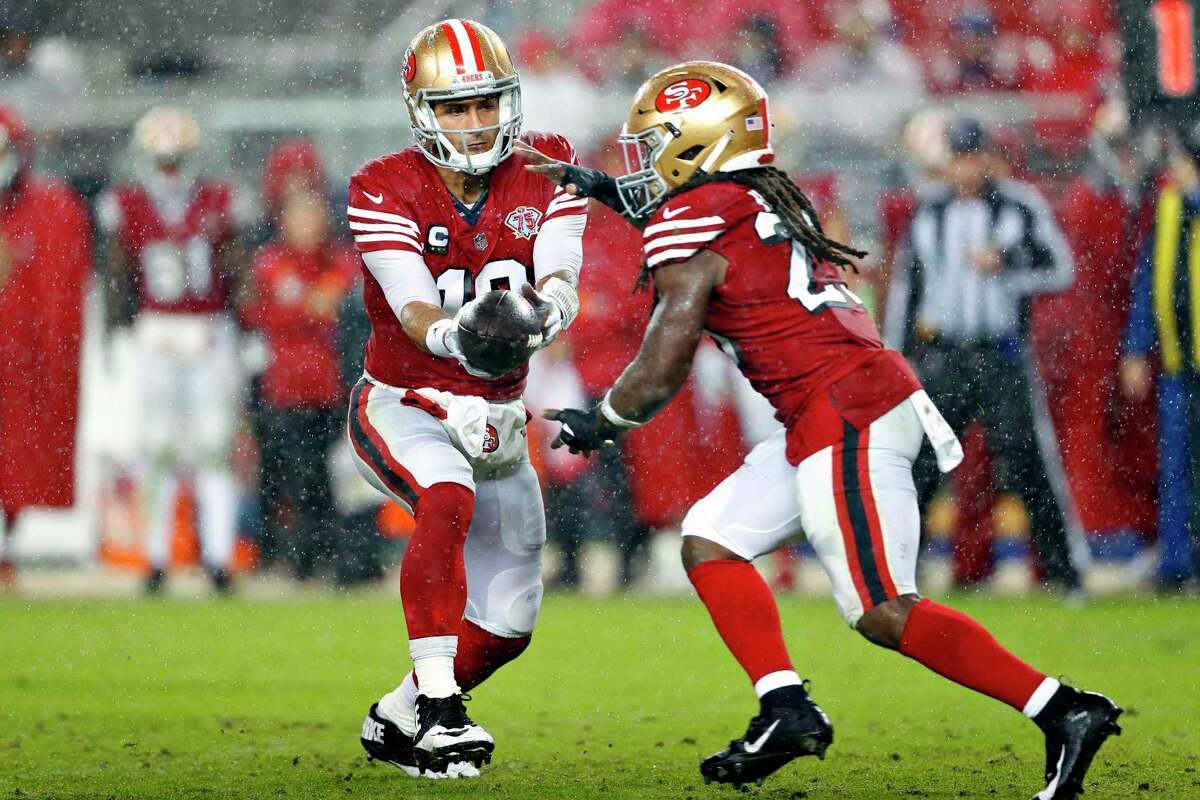 Jimmy Garoppolo of the San Francisco 49ers hands over Trey Sermon during the 30-18 loss to the Indianapolis Colts at Levi's Stadium in Santa Clara on Sunday, October 24, 2021.