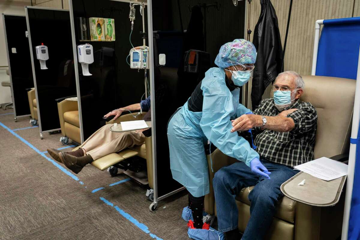RN Latoya Harris helps Samuel Levin, 91, finish receiving monoclonal antibody therapy, Friday, Jan. 21, 2022, at Houston Methodist Texas Medical Center in Houston.