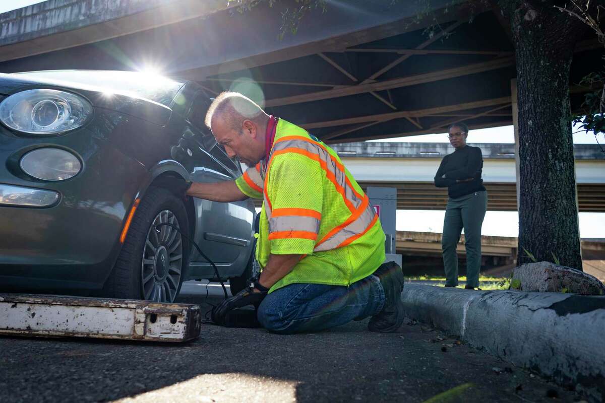 Tow and Go driver Rico Luna sees if he can fix the flat tire of driver Jasmine Hawkins’ car after pulling her to a safe place after she pulled over onto the northbound shoulder of 288 with a flat tire, Thursday, Jan. 13, 2022, near downtown Houston.