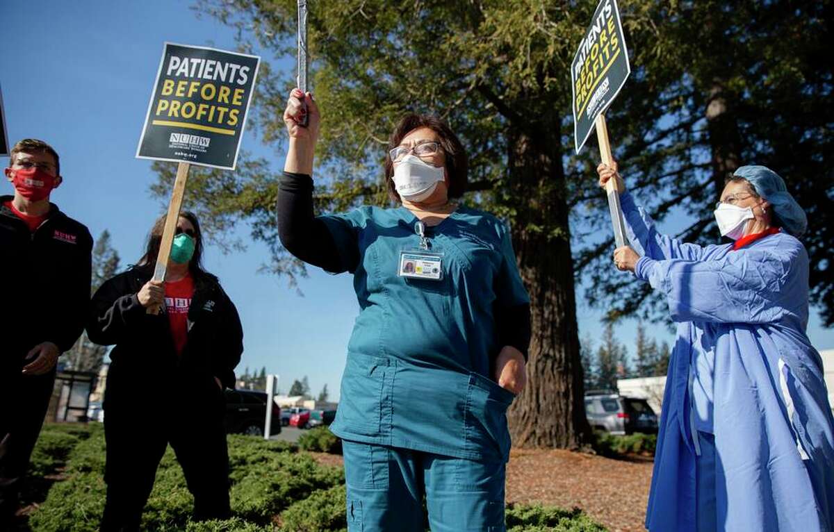 Rebecca Cleopas (center) and Martha Mcnelis (right), hospital staff at Providence Queen of the Valley Hospital, call for increased staffing and improved COVID safety measures during a Napa rally Wednesday.