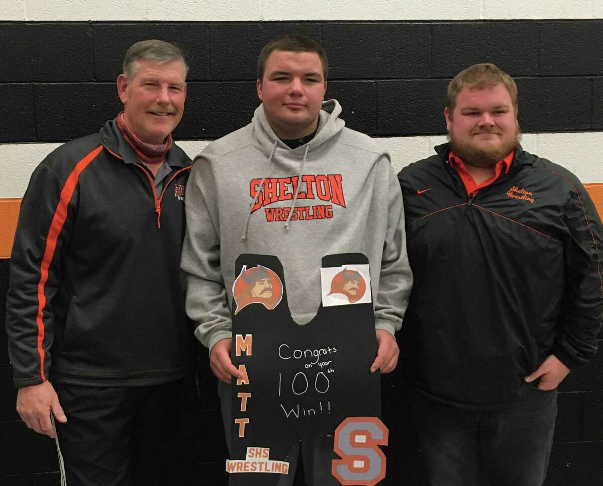Shelton senior heavyweight Matt Weiner is flanked by head coach Bill Maloney and assistant coach Rich Wigglesworth after earning his 100th career victory in a match with Jonathan Law.