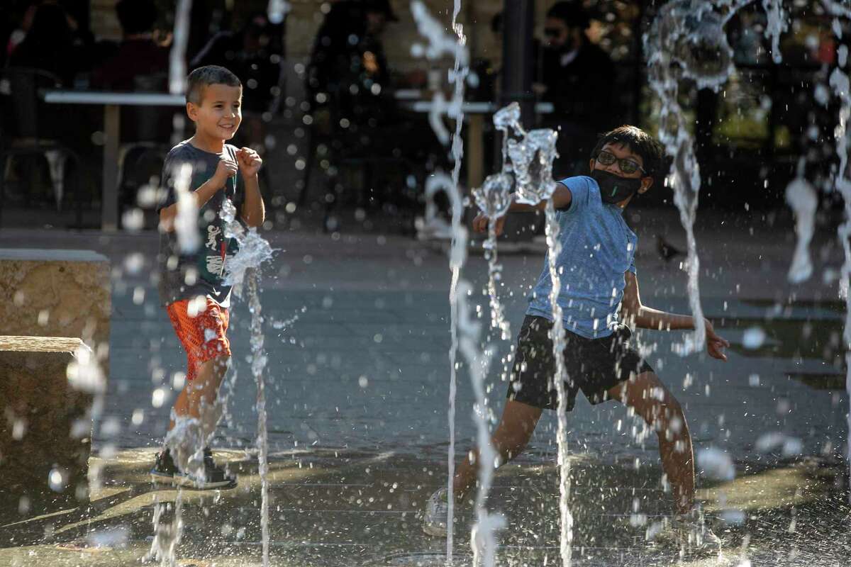 Caiden Gruber, 8, of Houston and his cousin Conner Jackson, 8, of San Antonio play in the splash pad at the Pearl Brewery in San Antonio on Dec. 22, 2021. Texas saw its hottest December since 1889, with an average daily temperature of 59 degrees Fahrenheit, according to the state’s climatologist.