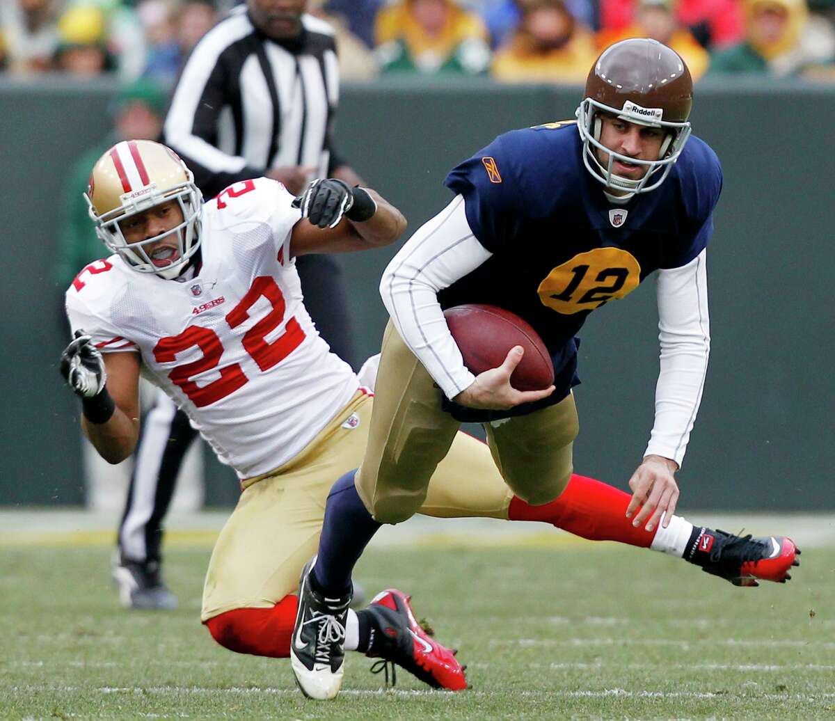 Green Bay Packers quarterback Aaron Rodgers (12) is tripped up by San Francisco 49ers cornerback Nate Clements (22) after a first down run during the second half of an NFL football game Sunday, Dec. 5, 2010, in Green Bay, Wis. The Packers won 34-16. (AP Photo/Jeffrey Phelps)