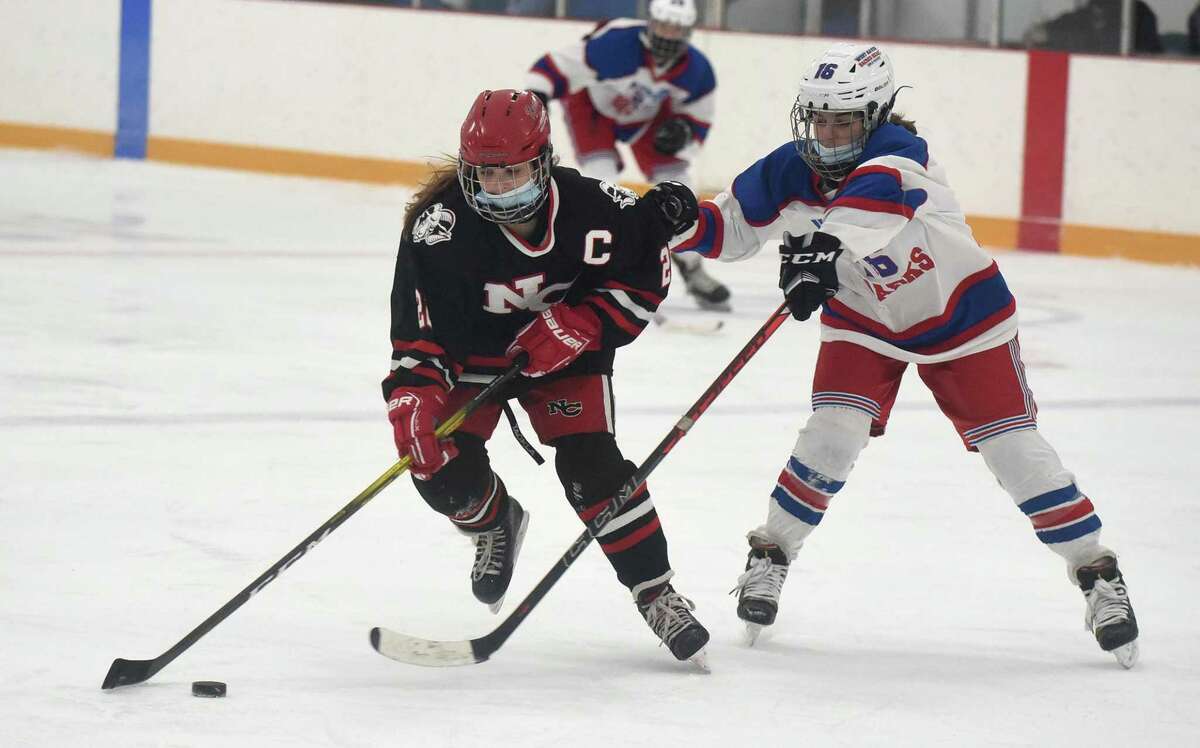 New Canaan’s Grace Crowell (22) and West Haven/SHA’s Juliann Picard (16) battle for the puck at Bennett Rink in West Haven on Saturday.
