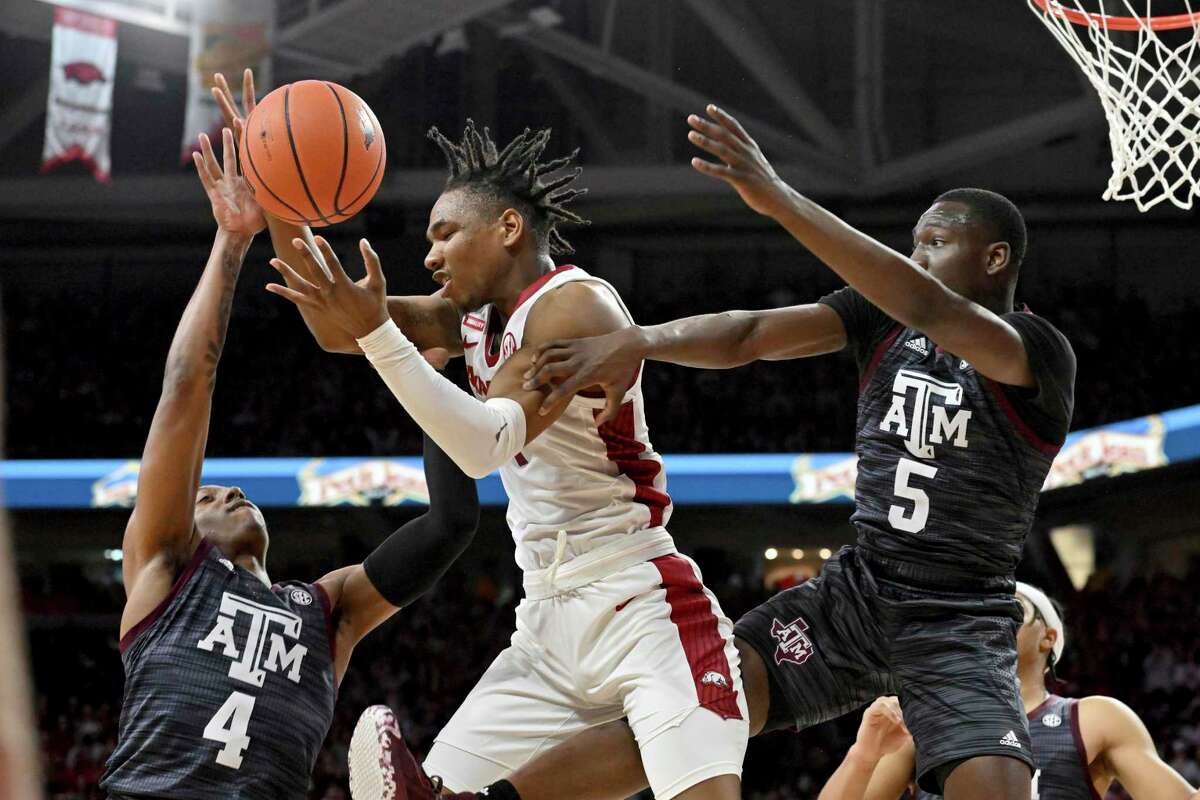 Arkansas guard JD Notae, center, fights for a rebound against Texas A&M’s Wade Taylor IV (4) and Hassan Diarra (5) during the first half Saturday, Jan. 22, 2022, in Fayetteville, Ark.
